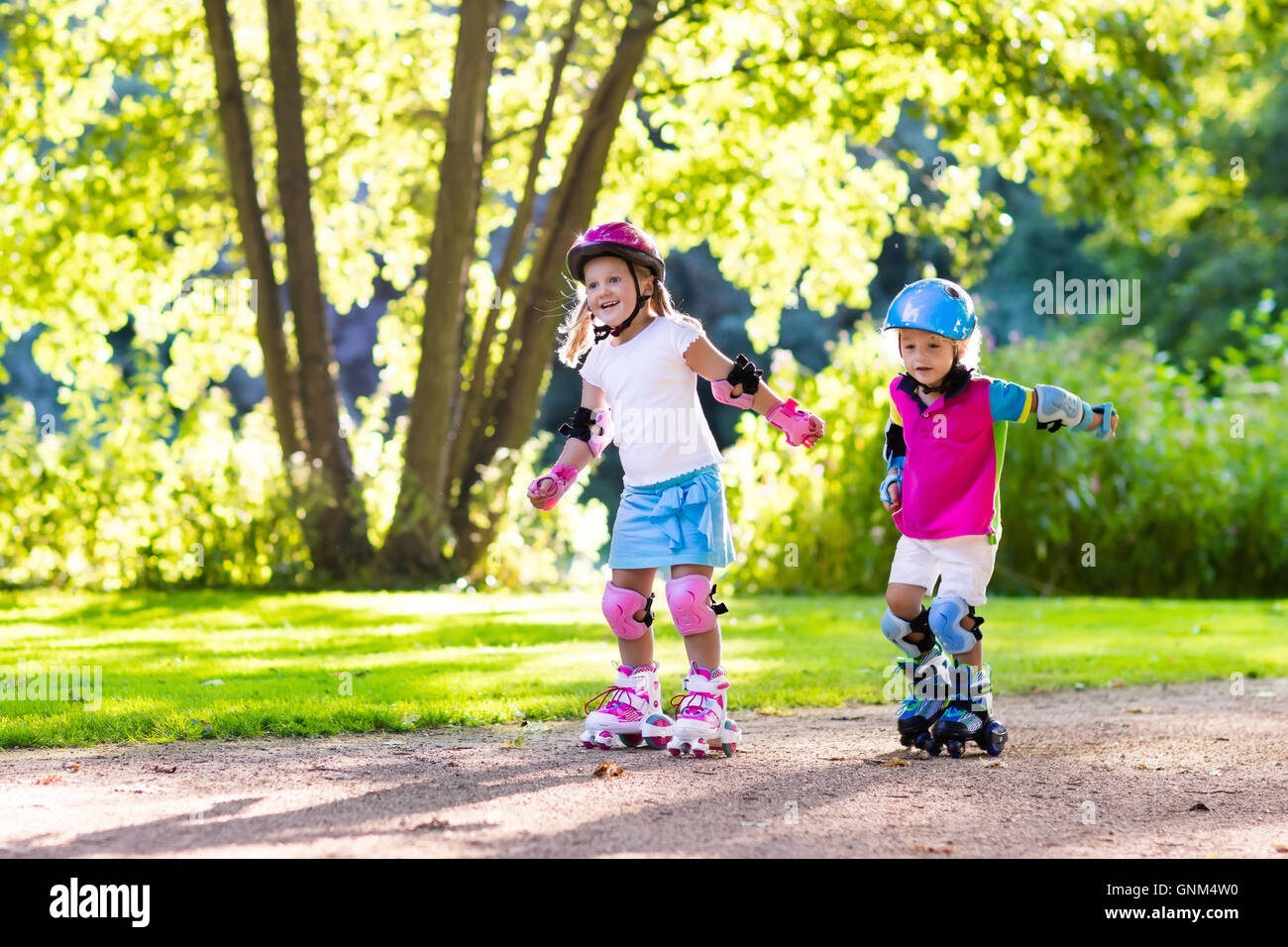 Girl and boy learn to roller skate in summer park. Children wearing