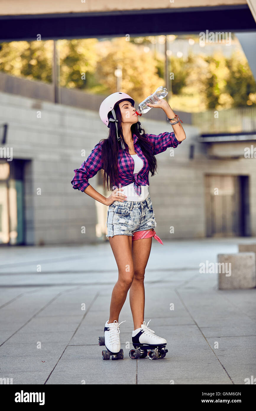 Young woman on roller skates and helmet drinking water Stock Photo