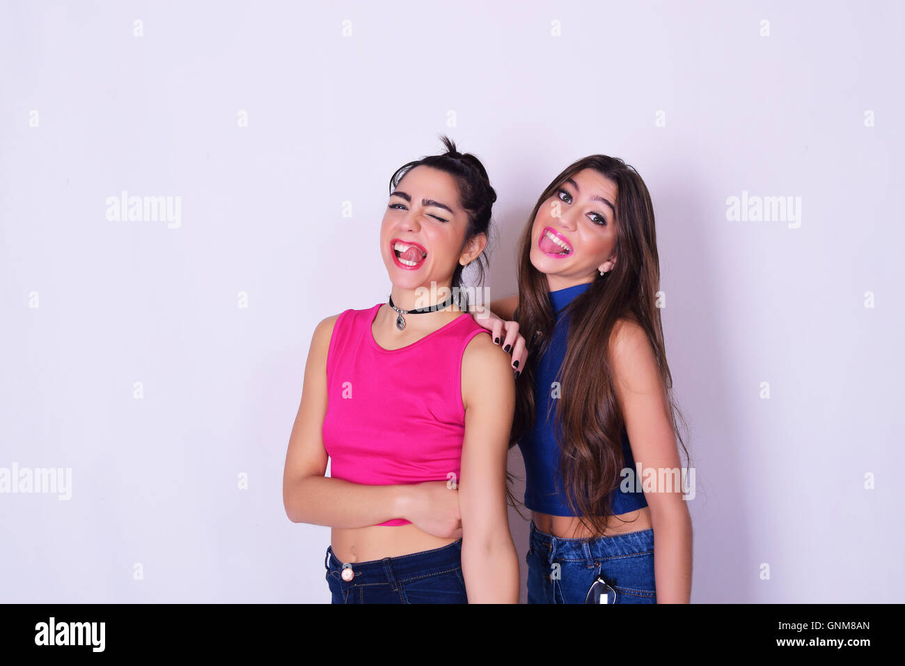 Portrait of two beautiful women having fun together. Friendship concept. Trendy and stylish friends isolated over grey backgroun Stock Photo
