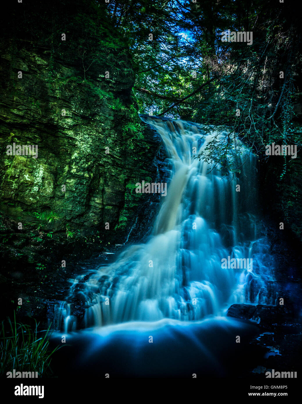 Electric Blue Waterfall in secluded woodland Stock Photo