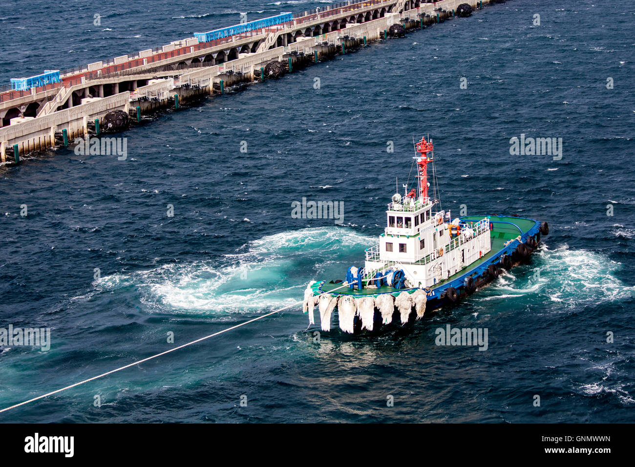 Tugboat prepares to tow cruise ship from difficult berth Stock Photo