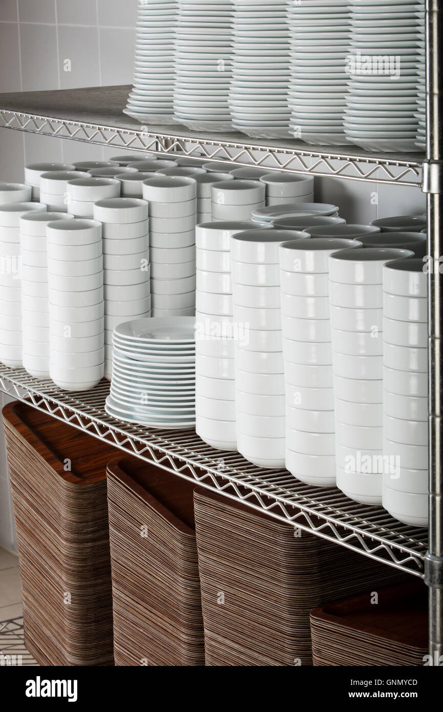 stacks of many white plates on a wire rack shelf in a commercial
