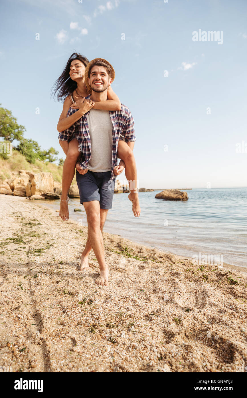 Lovely gay couple on piggyback ride at the beach. Stock Photo