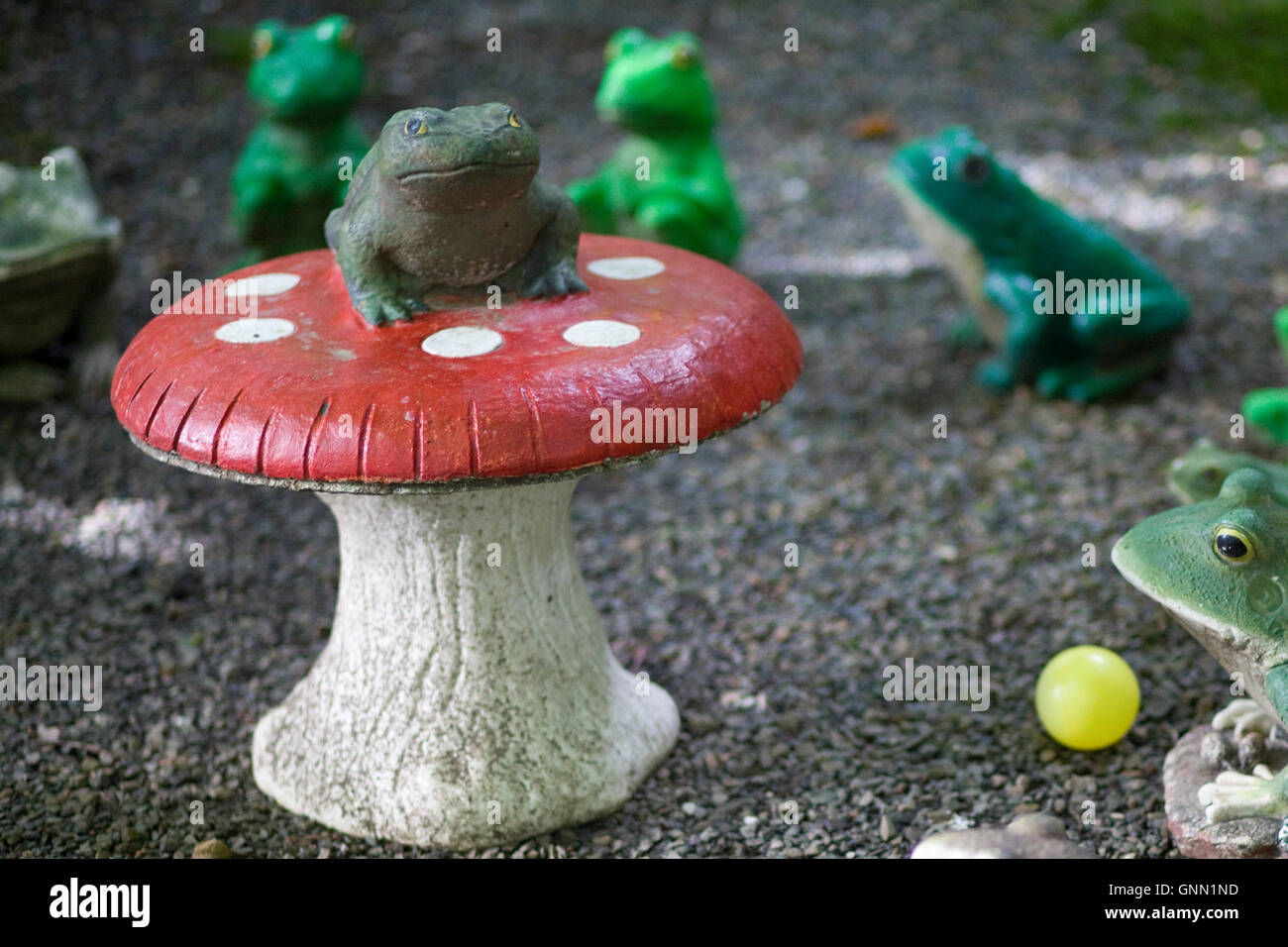 Statue of a toad sitting on top of a Fly agaric mushroom Stock Photo