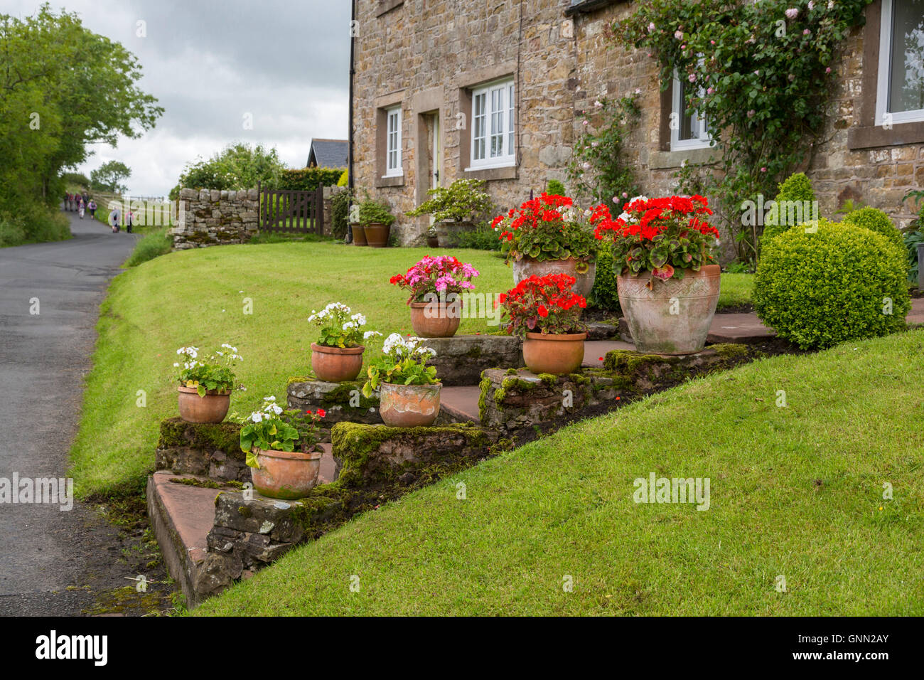 Banks, Cumbria, England, UK.  Village House on the Route of Hadrian's Wall Footpath.  Hikers in the Distance. Stock Photo
