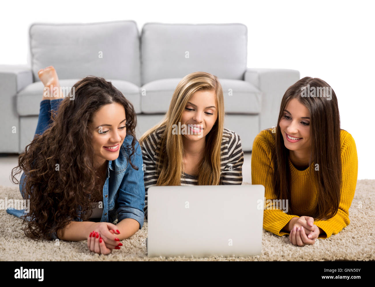 Happy teen girls studying at home with a laptop Stock Photo