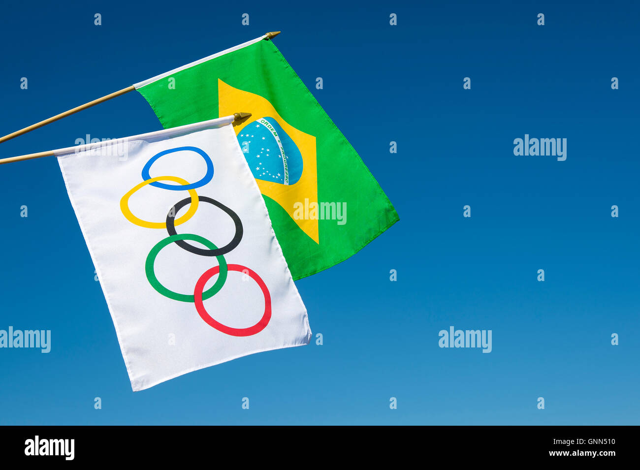 RIO DE JANEIRO - MARCH 27, 2016: Olympic and Brazil flags hang in bright blue sky in celebration of the city hosting the Games. Stock Photo