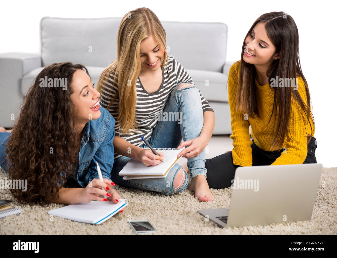 Happy teen girls studying at home with books and laptop Stock Photo