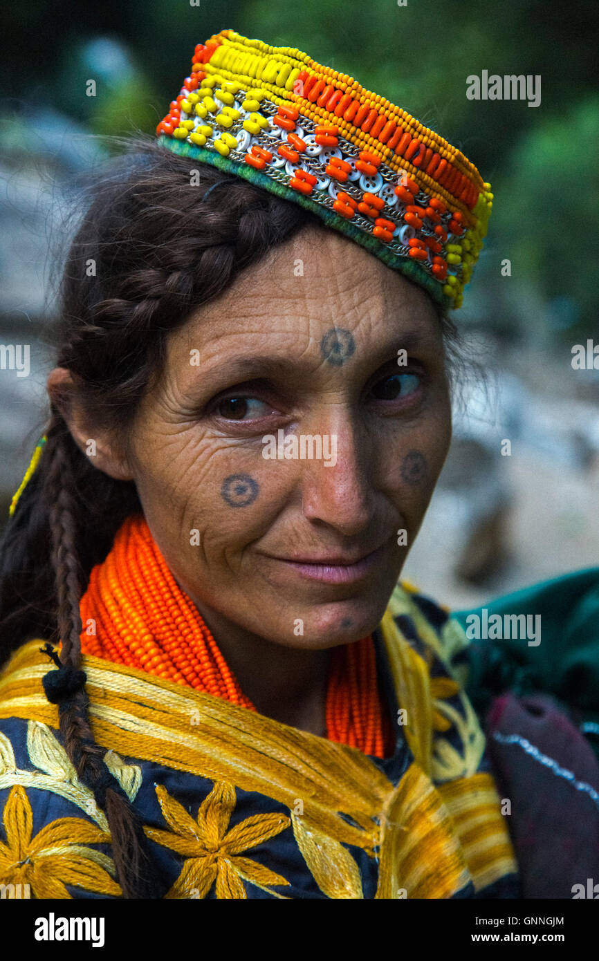 Beautiful Kalasha woman, with tattoos on her face, smiles whilst crossing the mountains of Kalash Valley in Chitral, Pakistan Stock Photo