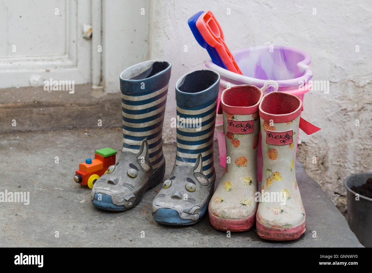 children's wellington boots and bucket and spade on a doorstep Stock Photo
