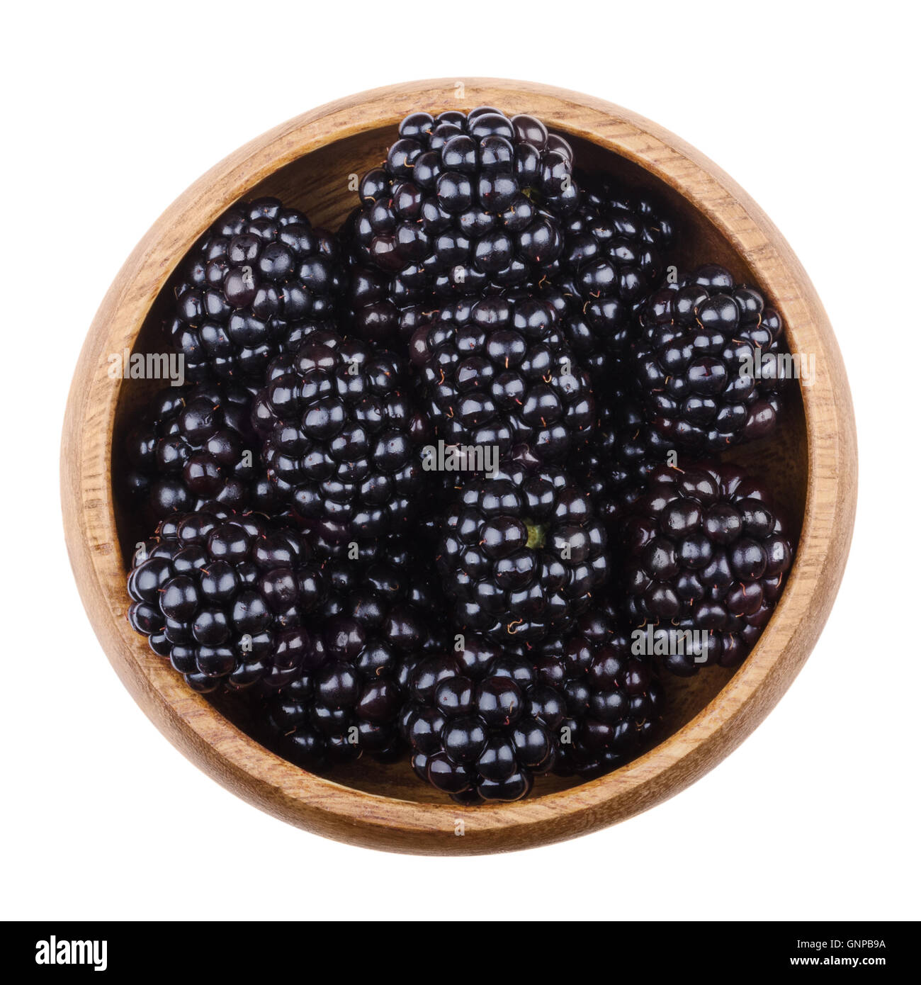 Blackberries in a wooden bowl on white background. Black edible ripe fruit of Rubus fruticosus. Stock Photo