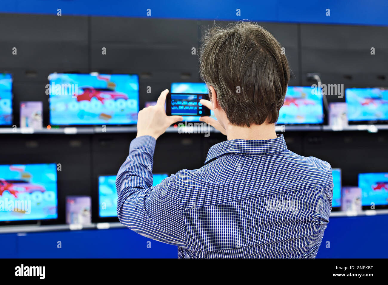 Man shoots with a smartphone TVs in shop Stock Photo