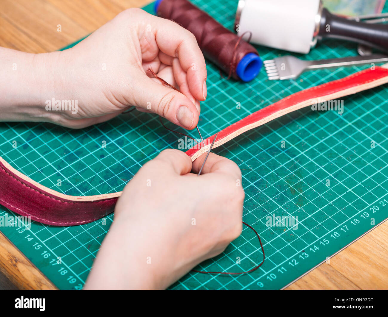 leatherworking skinner sews new leather belt Stock Photo Alamy