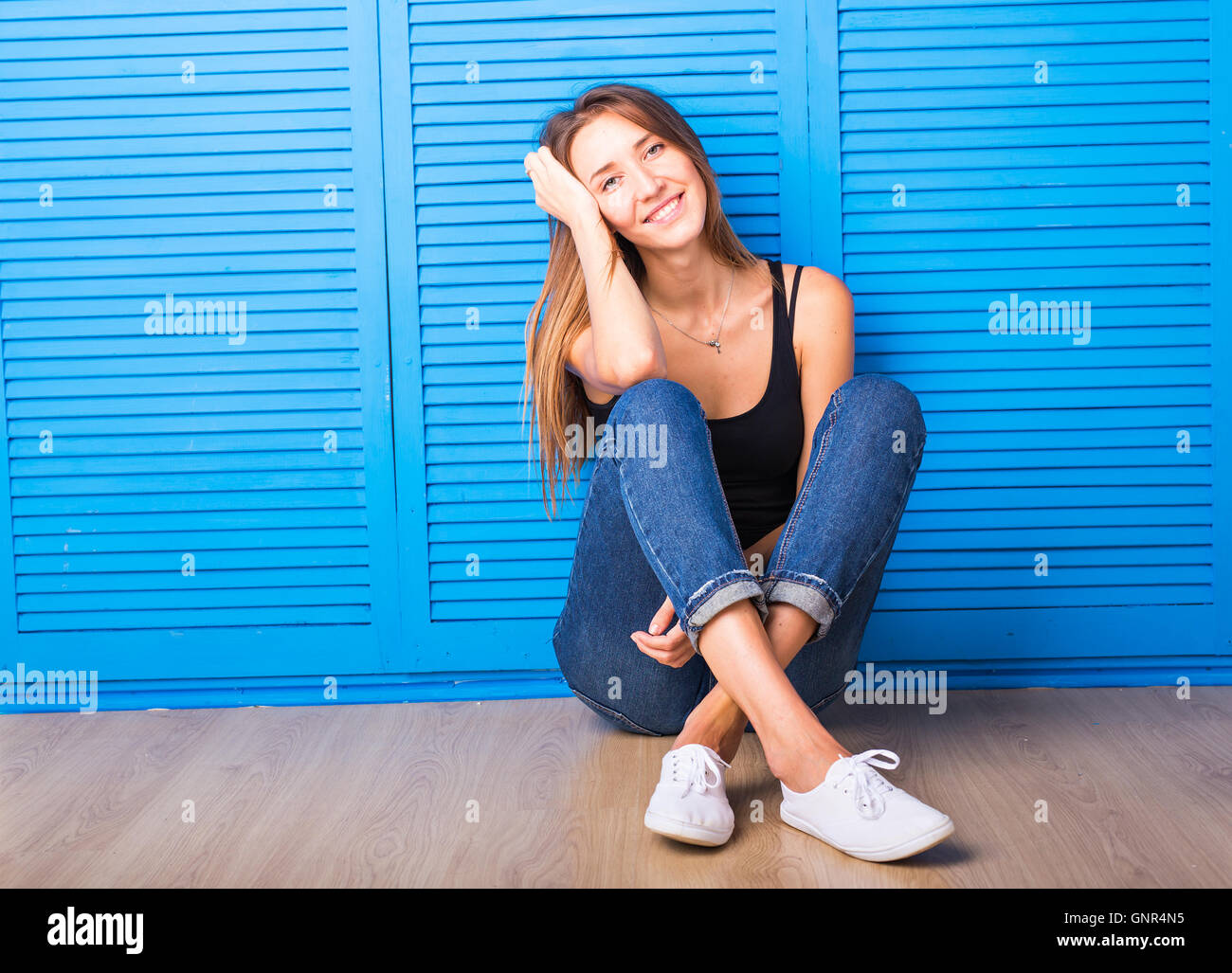 young pretty woman sitting on the floor against blue background Stock ...