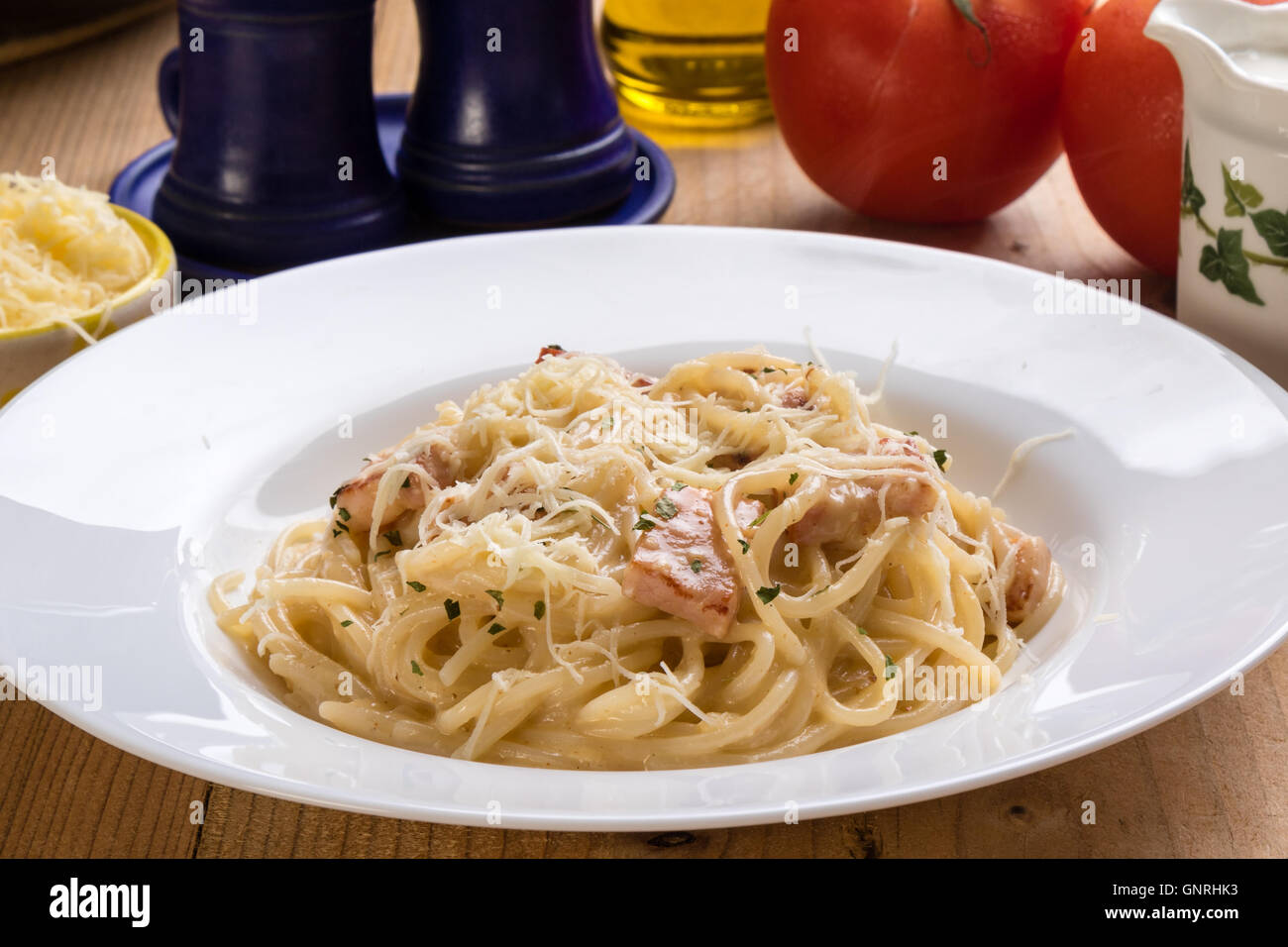 spaghetti carbonara on wooden table with rustic setting Stock Photo