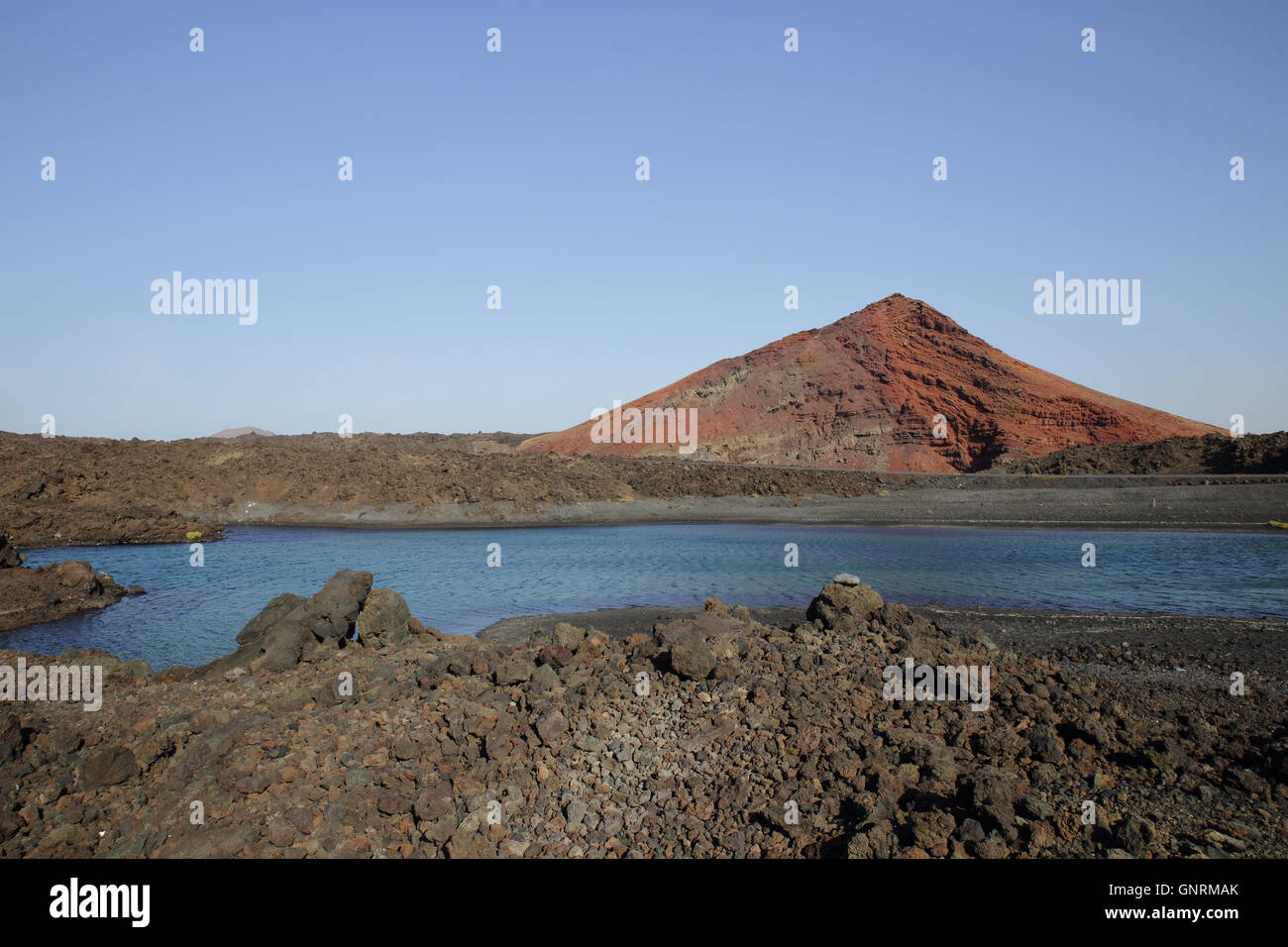 overview of a little lake in the lava near Playa Bermeja  in front of a vulcan of Timanfaya National Park, Stock Photo