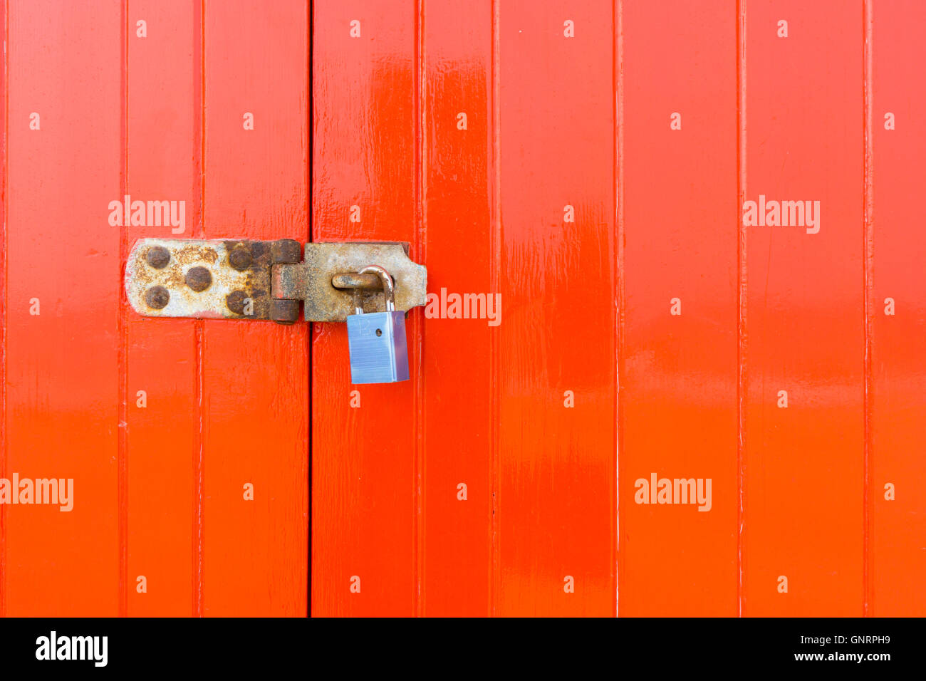 Padlock and latch on a bright red wooden closed door Stock Photo