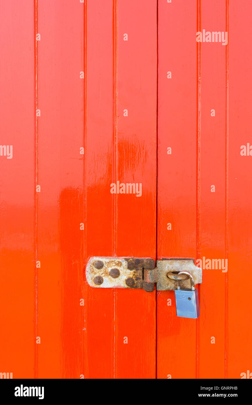 Padlock and latch on a bright red wooden closed door Stock Photo