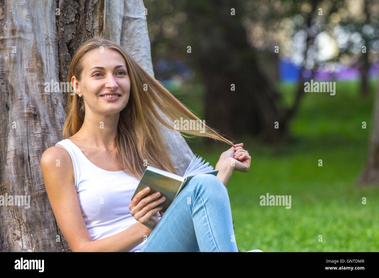 Young woman sitting on the grass and reading book outdoor Stock Photo ...