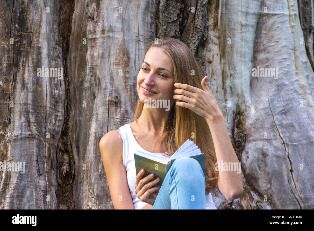 Young woman sitting on the grass and reading book outdoor Stock Photo ...