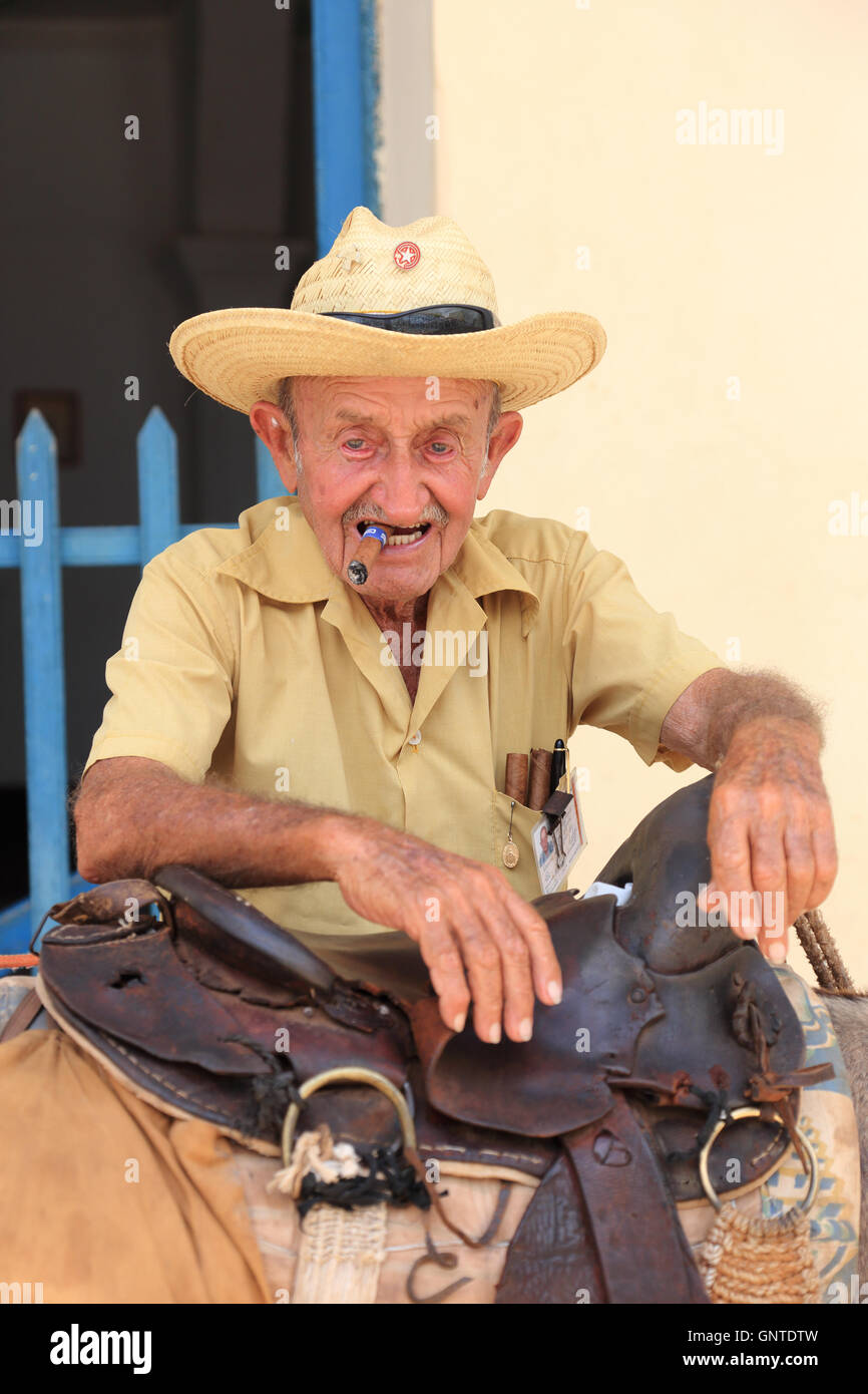 Old gentleman with Cuban cigar leaning on his donkey in Trinidad, Cuba Stock Photo