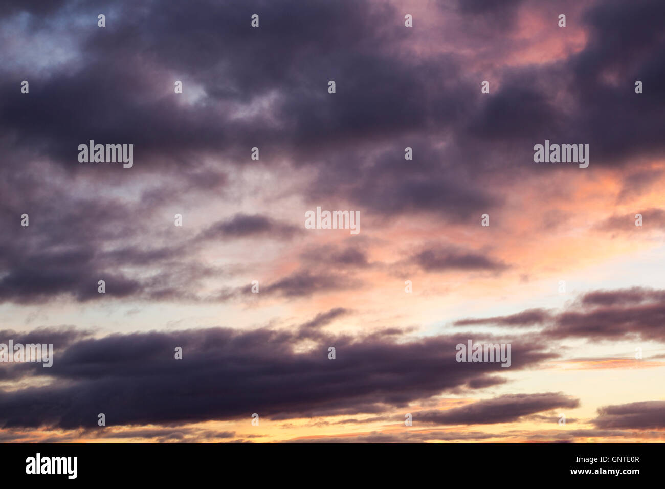 Colourful cloudscape at daybreak with purple, pink and yellow colours dominant Stock Photo