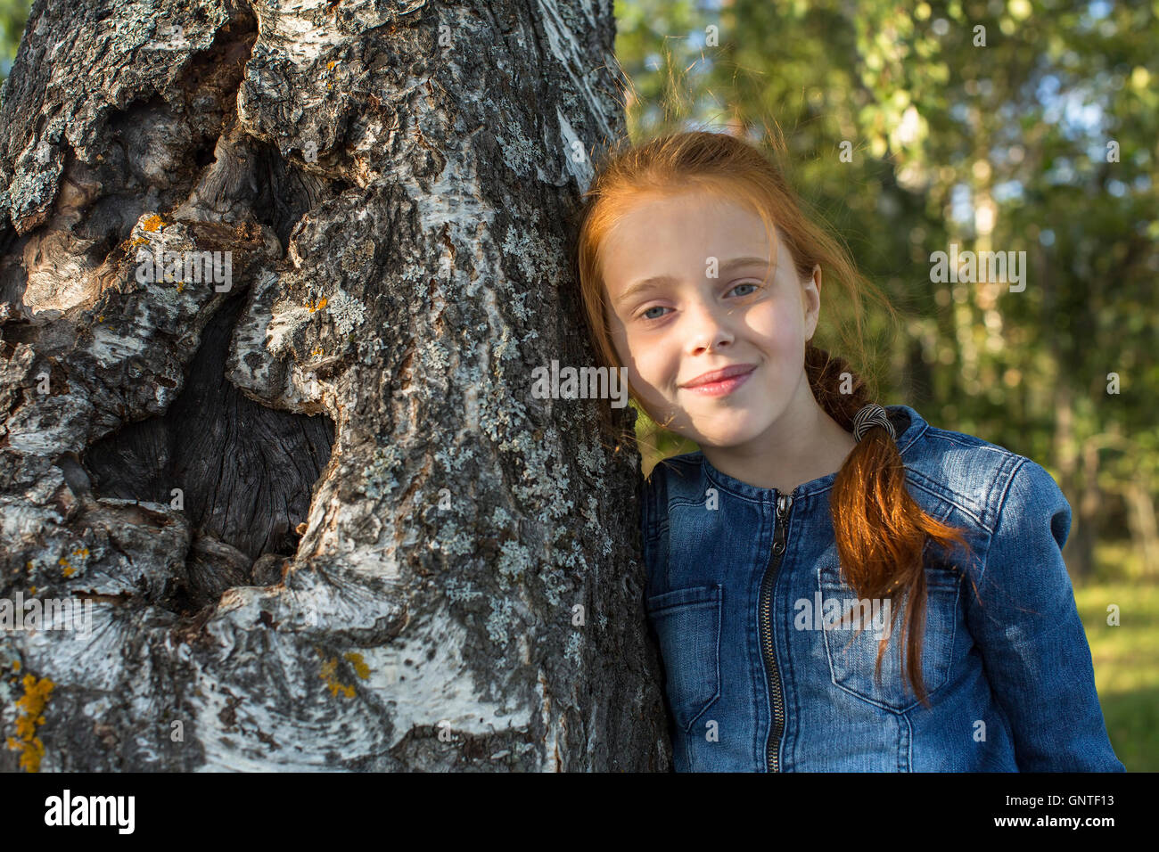 Closeup portrait of red-haired little girl in the woods. Stock Photo