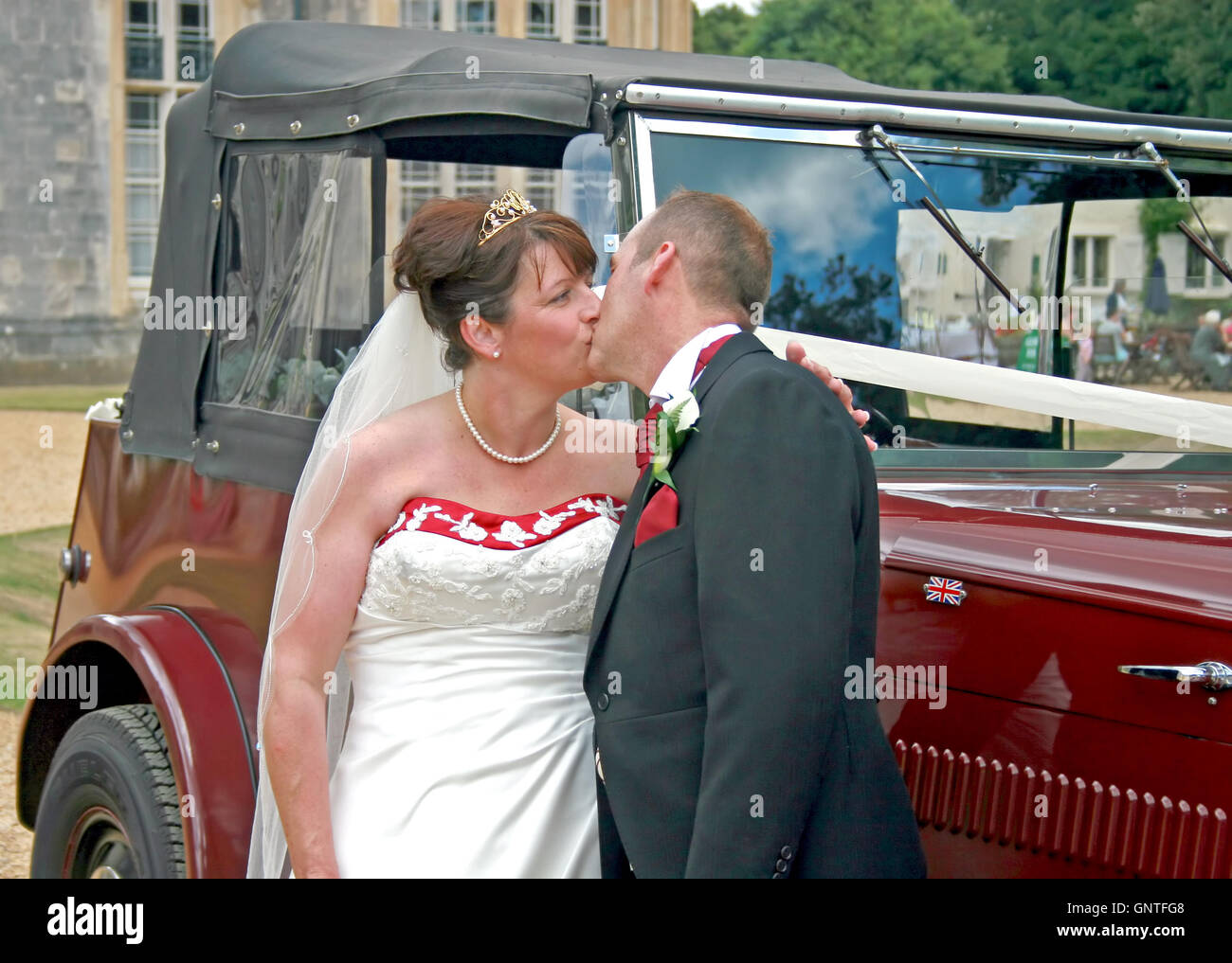 Bride and Groom kissing in front of their wedding car Stock Photo - Alamy