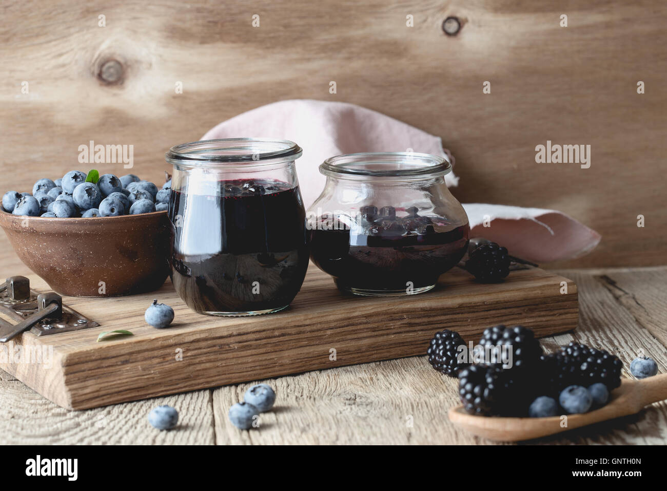 Homemade blueberries and blackberries jam in glass jars and fresh