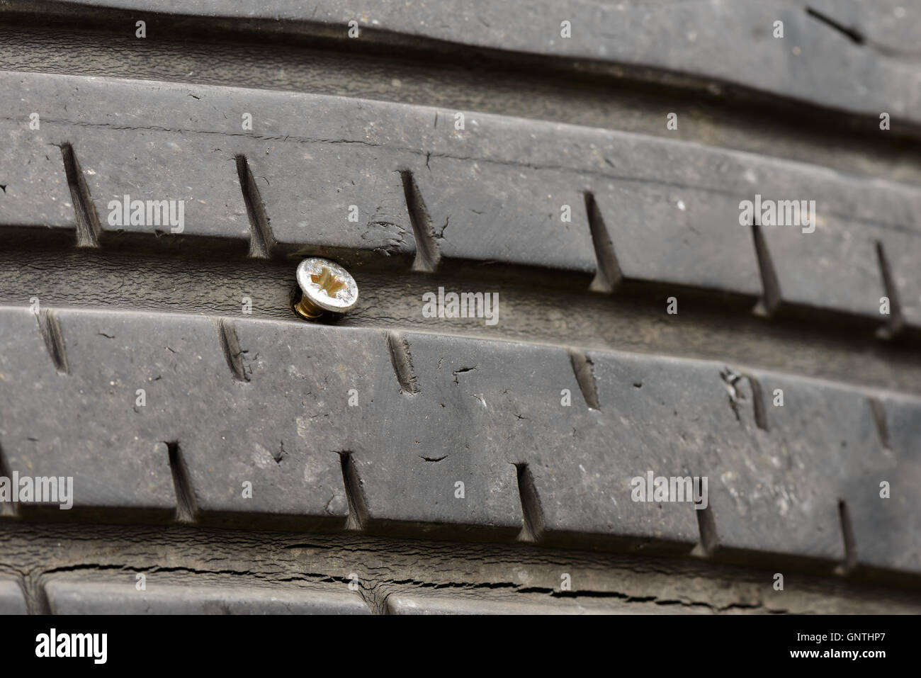 A flat tire by a little long screw Stock Photo