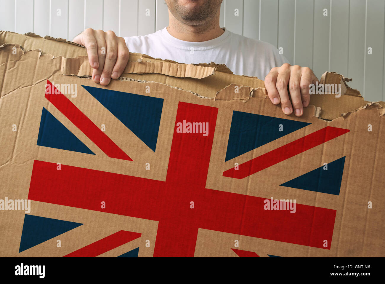 Man holding cardboard with United Kingdom flag printed, adult male person supporting Great Britain Stock Photo