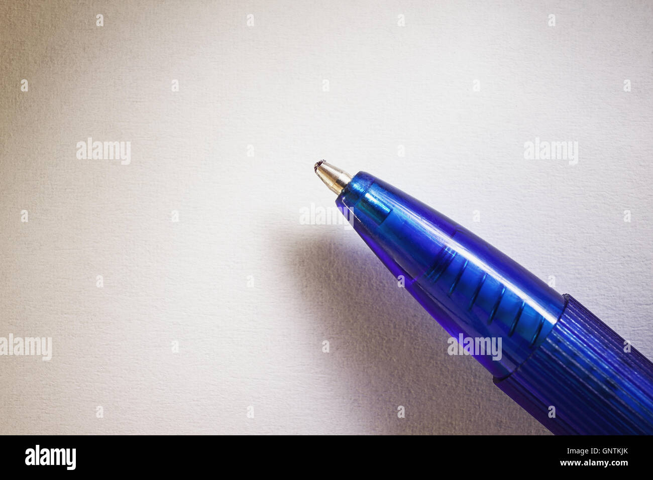 Closeup view of a blue ball pen on white paper. Stock Photo