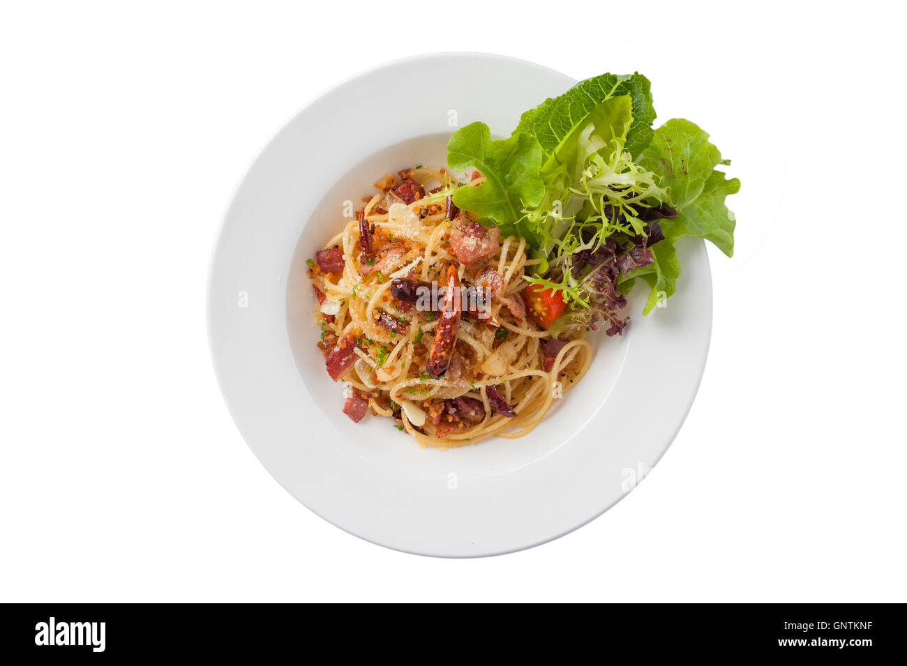 Top view of Thai, Japanese, and European fusion food style spicy pasta with bacon and dried chili in ceramic dish isolated on wh Stock Photo