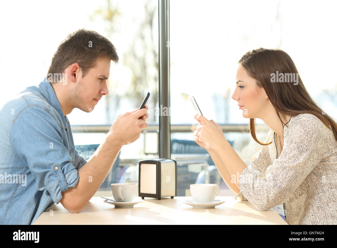 Side view of a couple on line everyone obsessed with their own smart phones in a coffee shop Stock Photo