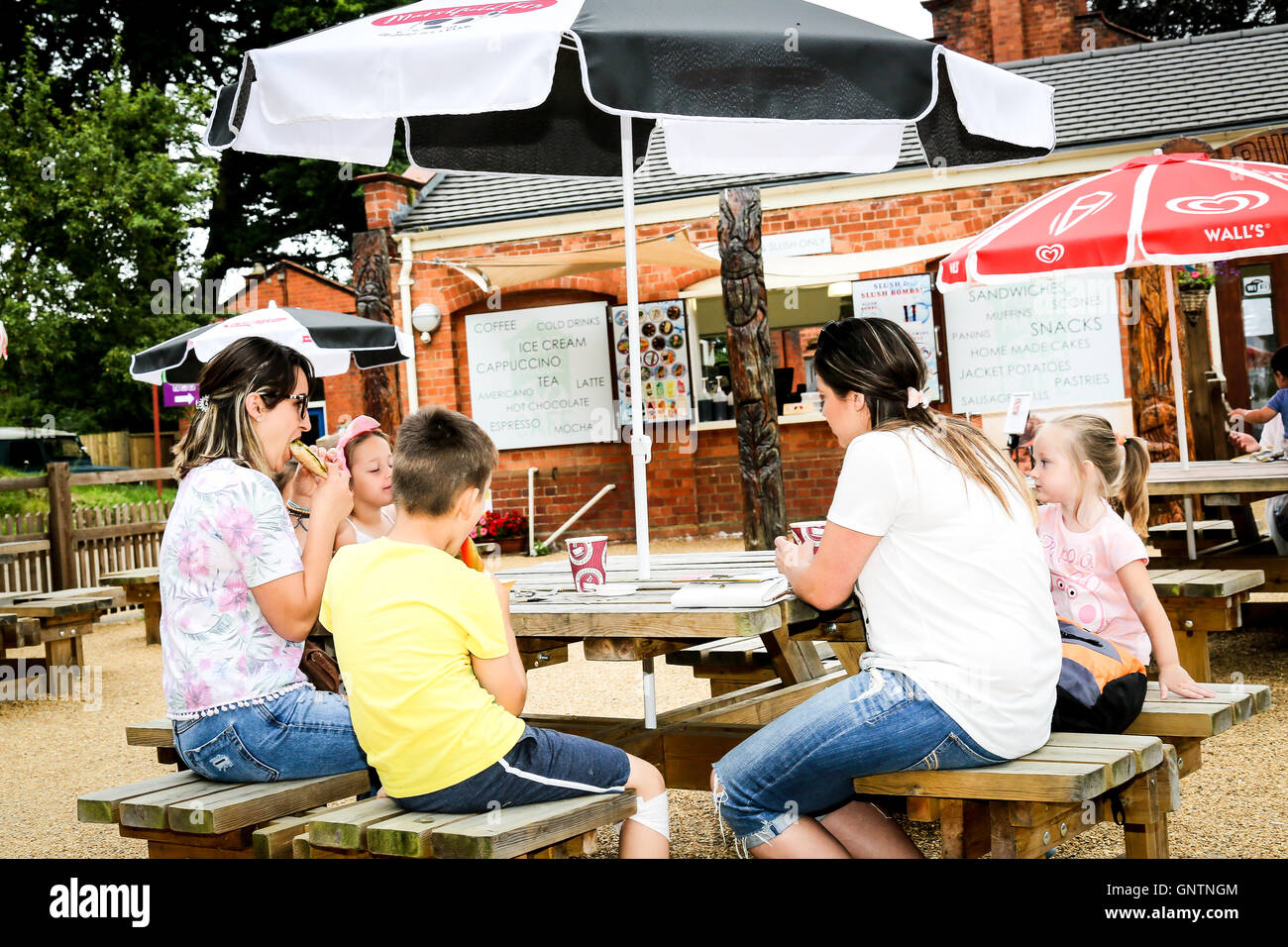 A young family enjoying a snack at an outdoor cafe in the summer Stock Photo