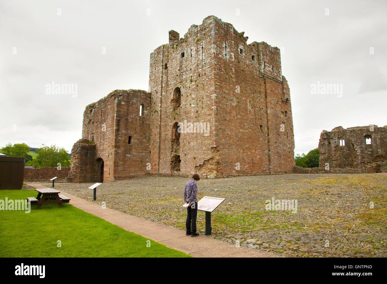 Brougham Castle keep. Woman looking at tourist sign. Penrith, Cumbria