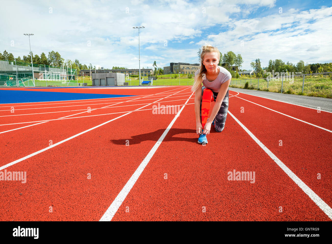 Confident Woman Tying Shoelace On Running Tracks Stock Photo