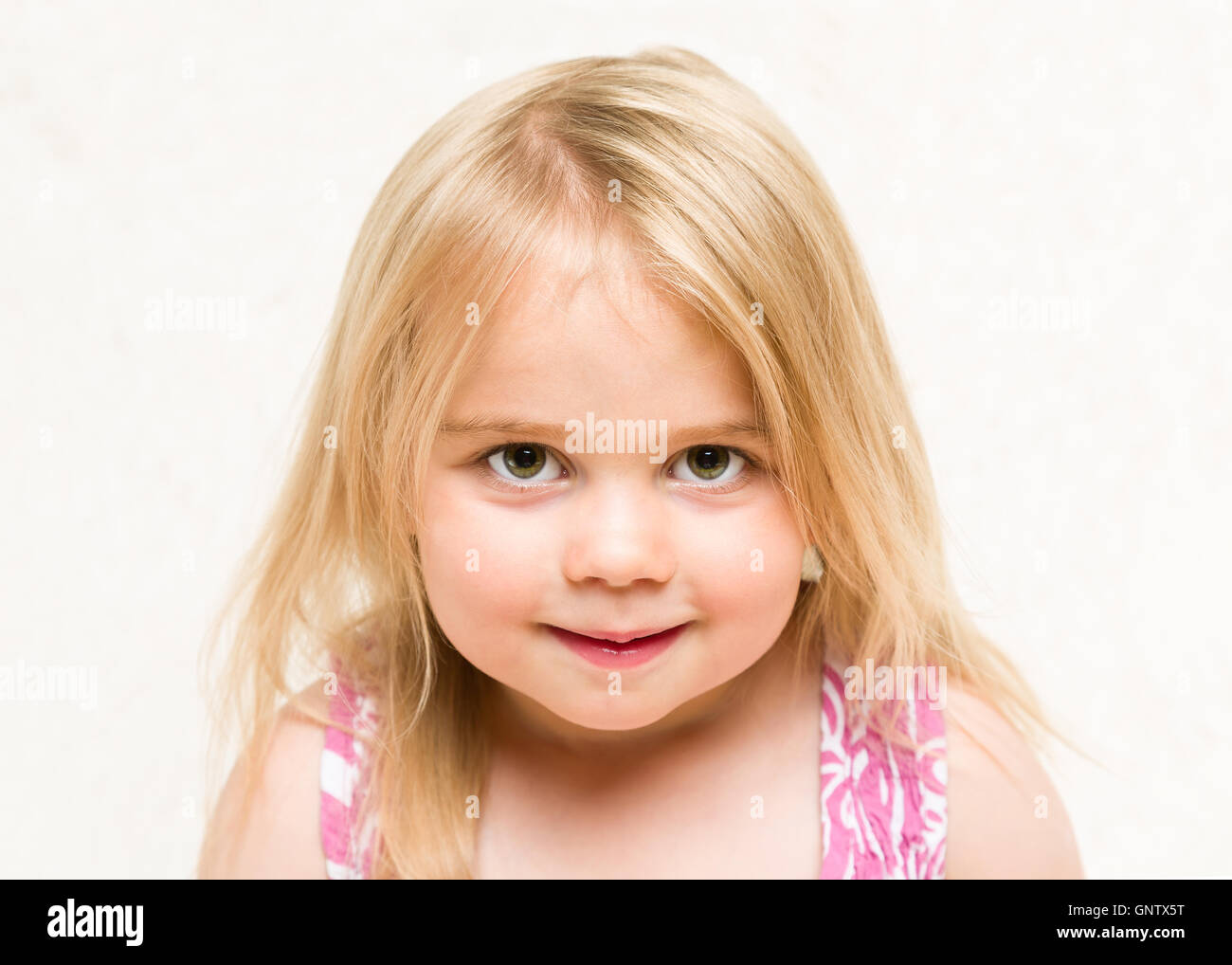 Closeup portrait of beautiful blonde toddler baby girl with cheeky grin Stock Photo