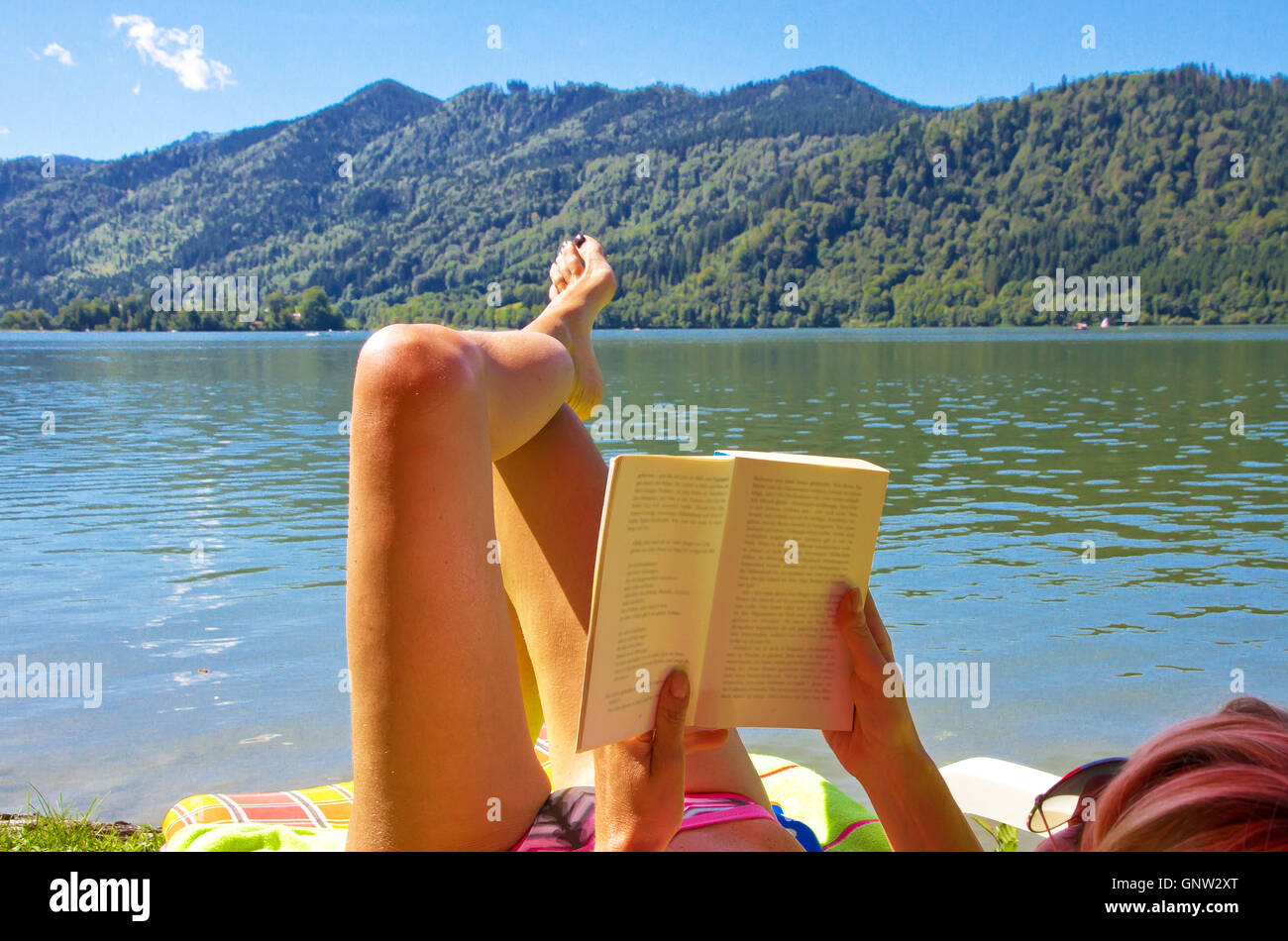 Woman lying on a lake and reading a book Stock Photo