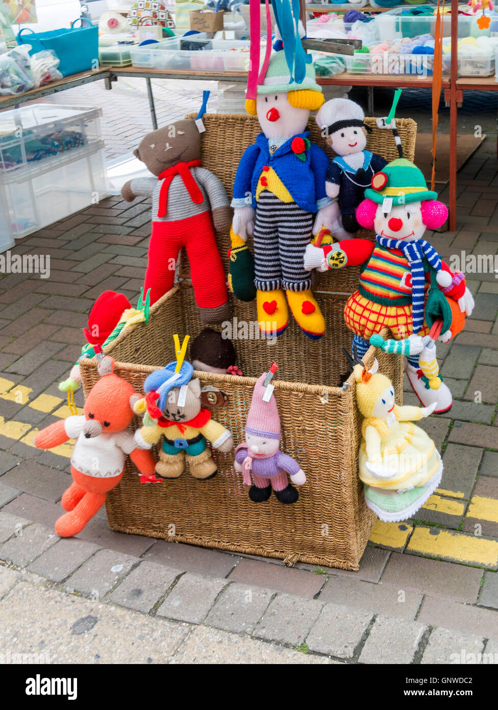 Display of colourful knitted cuddly dolls for sale on a market stall