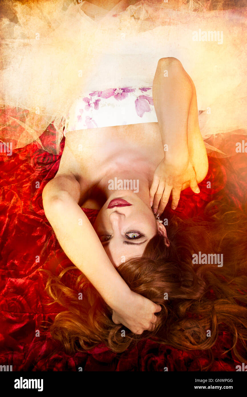 sensual woman with long red hair lying on a bed of flowers Stock Photo ...