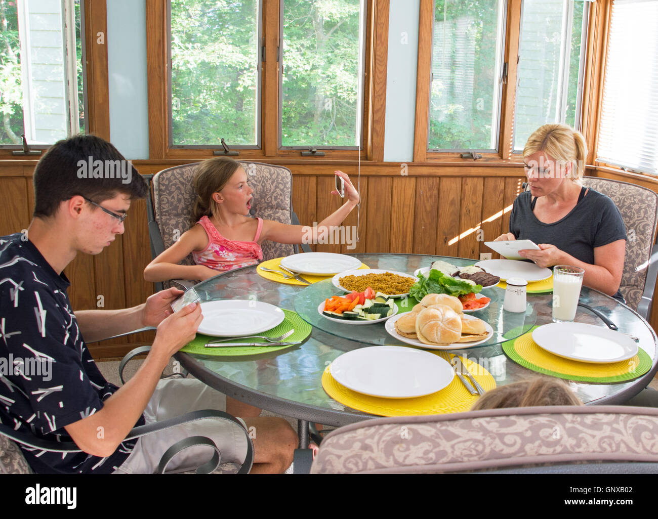 Modern family at the dinner table on electronic devices Stock Photo - Alamy
