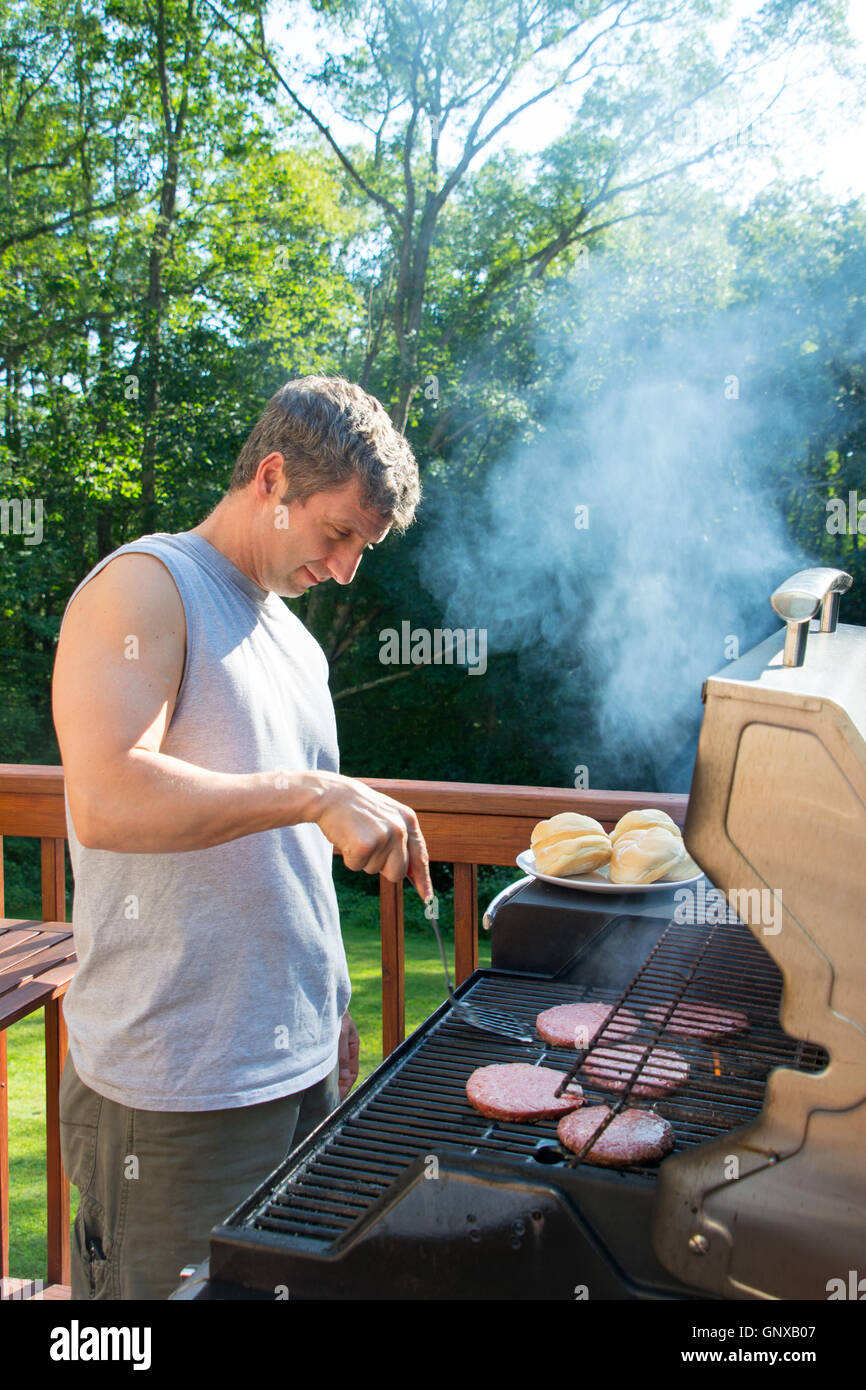 Uomo che indossa un grembiule lavorando la griglia per il barbecue Foto  stock - Alamy