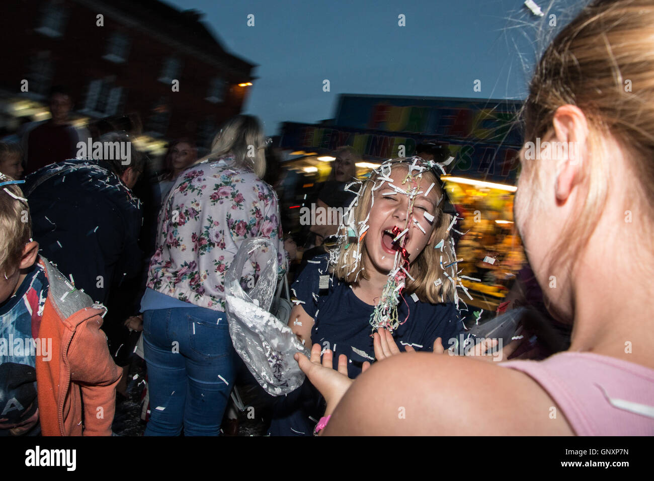 Devizes Wiltshire, UK. 31st Aug, 2016. People throwing confetti during the confetti battle event. Confetti is fired over the crowd gathered in the market square and supplies also available for throwing around. Now part of the Devizes International Street Festival the tradition has been a part of the annual Devizes Street Carnival celebrations since 1955 and stems from the former practice of throwing rose petals at carnival floats. Credit:  Paul Francis/Alamy Live News Stock Photo