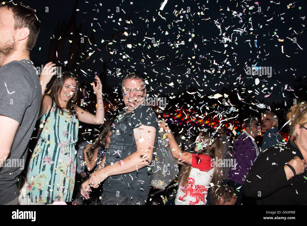 Devizes Wiltshire, UK. 31st Aug, 2016. People throwing confetti during the annual confetti battle event. Confetti is fired over the crowd gathered in the market square and supplies are also available for throwing around. Now part of the Devizes International Street Festival the tradition has been a part of the annual Devizes Street Carnival celebrations since 1955 and stems from the former practice of throwing rose petals at carnival floats. Credit:  Paul Francis/Alamy Live News Stock Photo
