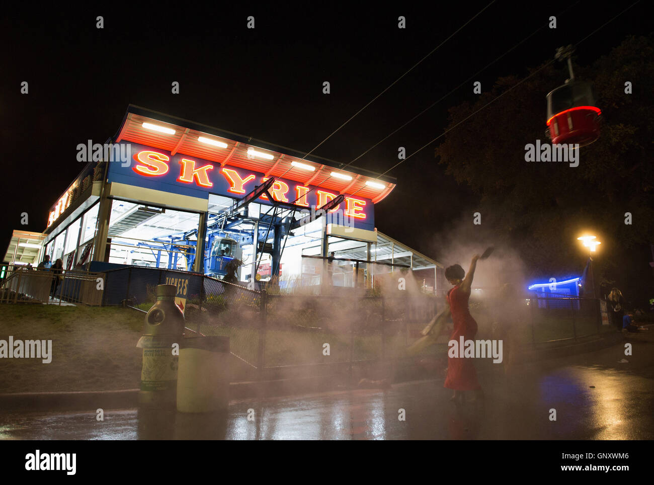 St. Paul, Minnesota, USA. 31st August, 2016. A woman in a red dress cools off in misty water underneathh the skyride at the Minnesota State Fair. © Gina Kelly / 17�Թ����� Live News Stock Photo
