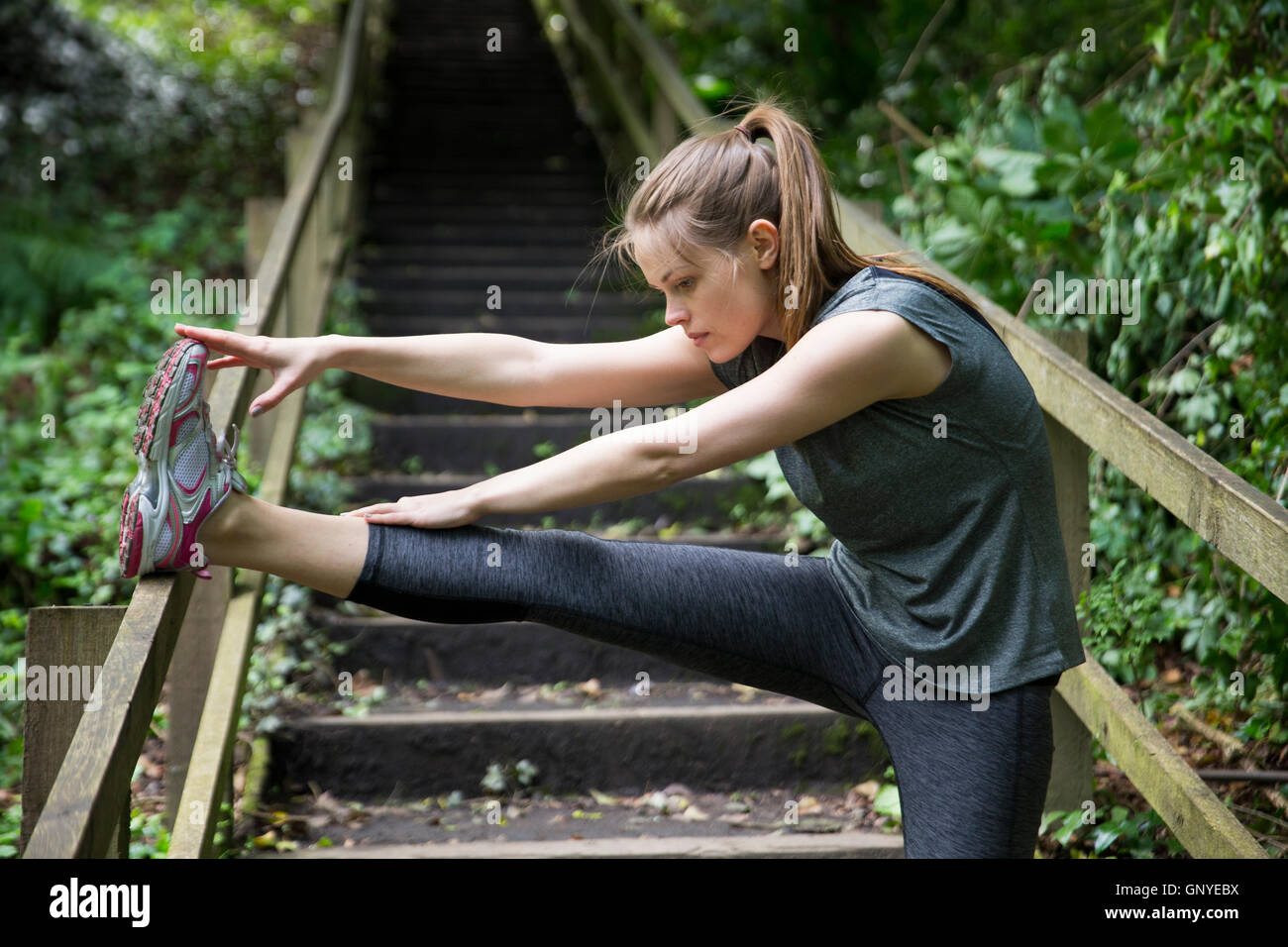 Woman stretching before running on a forest trail, training and exercising. Fitness healthy lifestyle concept with female athlet Stock Photo