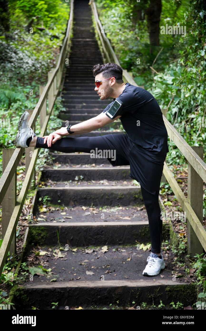 Man stretching before running on a forest trail, training and exercising. Fitness healthy lifestyle concept with male athlete. Stock Photo
