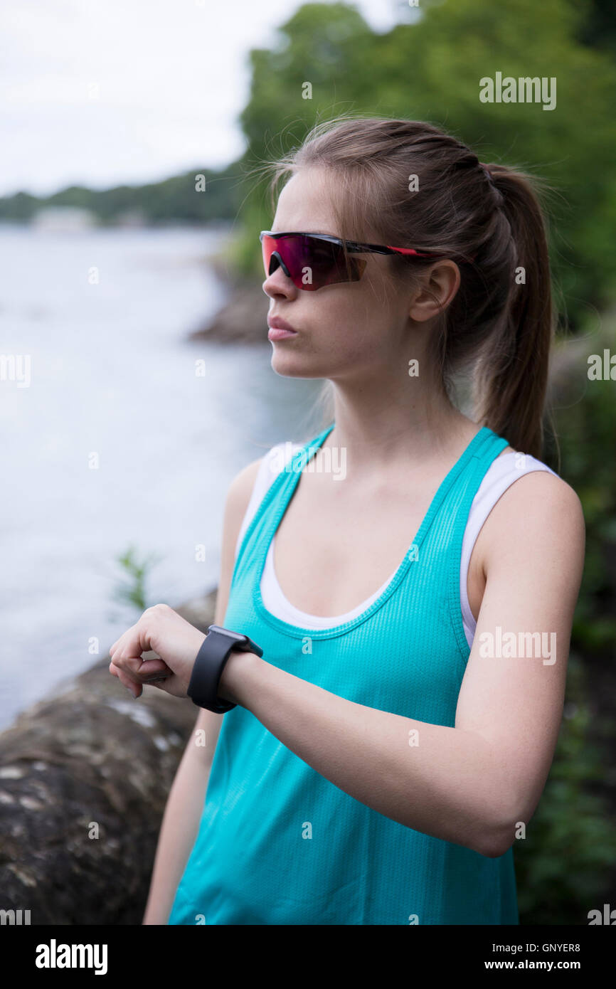 Woman out running on forest trail, using her smart watch heart rate monitor. Fitness healthy lifestyle concept with female athle Stock Photo