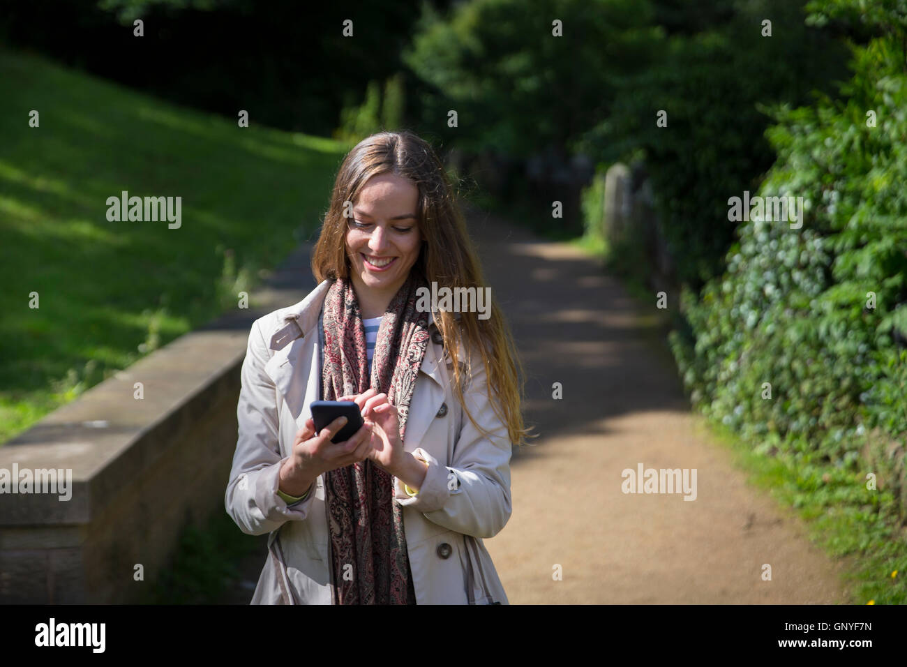 Happy woman walking and using her smart phone in the street. Caucasian female lifestyle concept. Stock Photo
